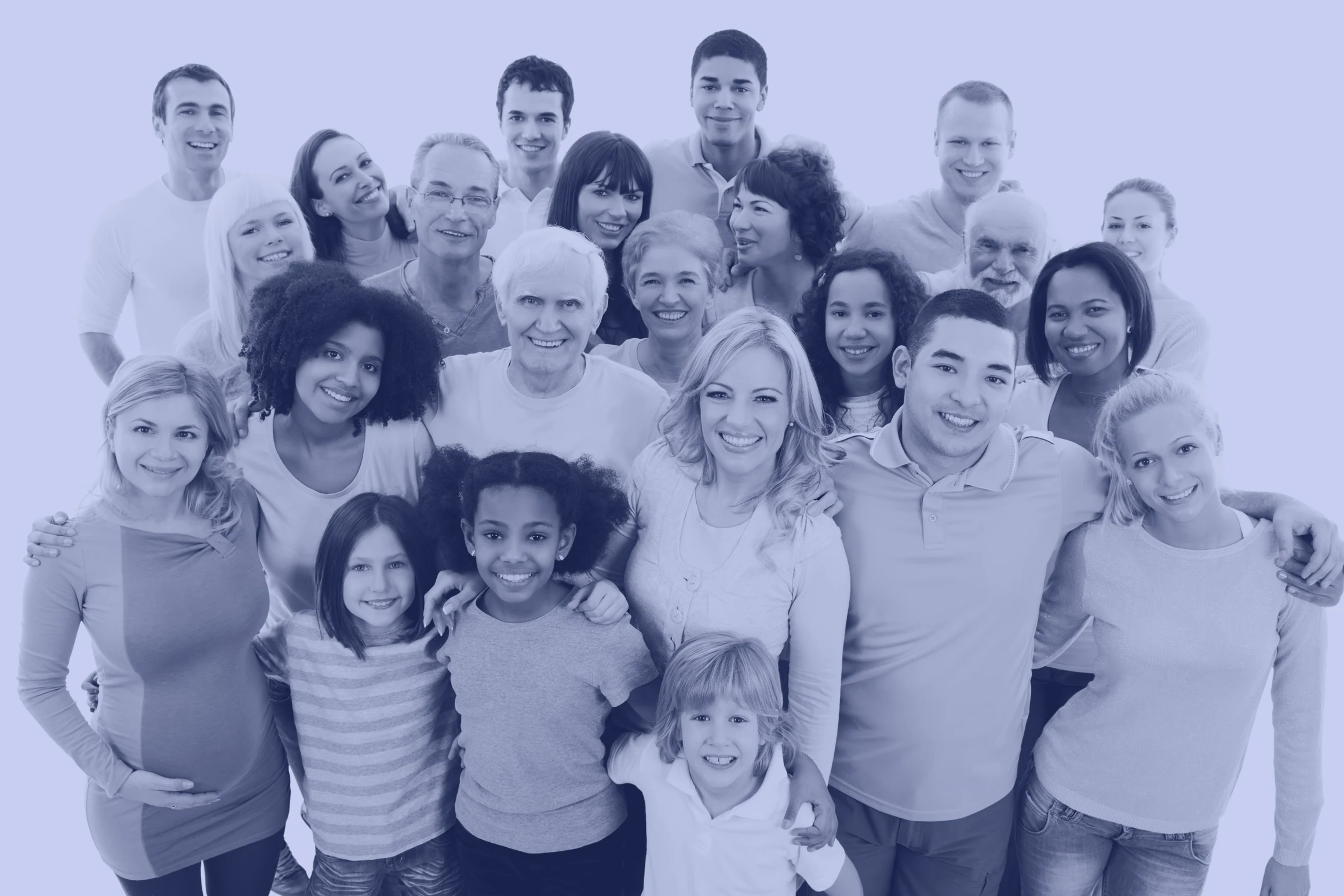 A large multi-generational group of people standing close together and smiling at the camera: three children in the front row, adults behind them, and a pregnant woman at the left with a hand on her belly.